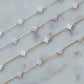 Two necklaces with clover-shaped opal beads on a marble surface