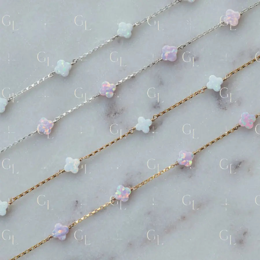 Two necklaces with clover-shaped opal beads on a marble surface