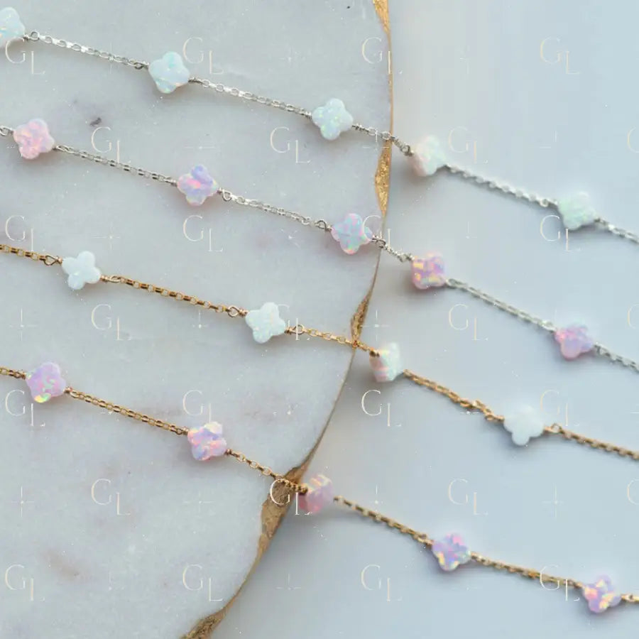Gold chain necklace with pink and white beaded extensions on a marble surface
