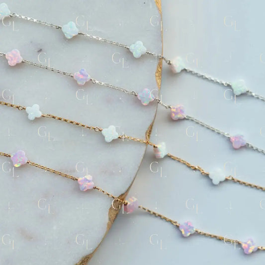 Gold chain necklace with pink and white beaded extensions on a marble surface