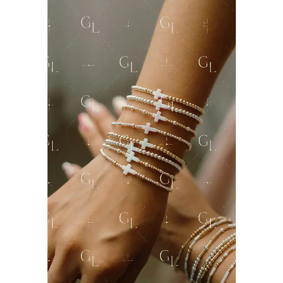 Close-up of a wrist wearing multiple delicate bracelet with cross designs.