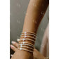 Close-up of a wrist wearing multiple pearl bracelets with cross designs.