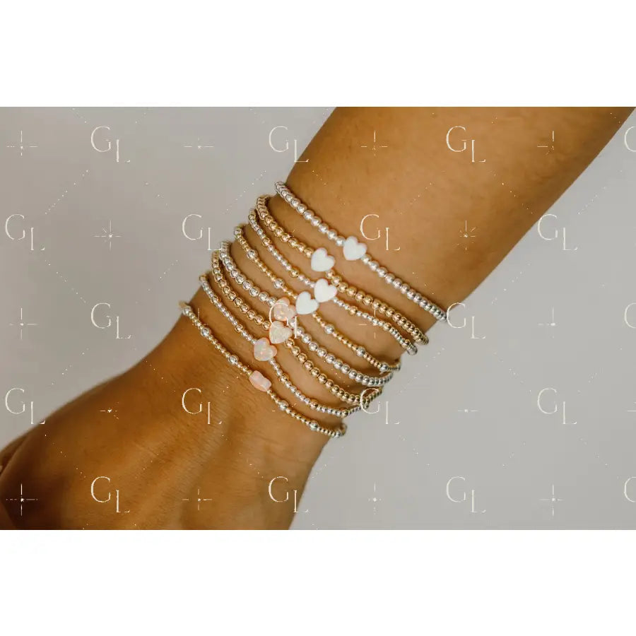 Close-up of a wrist wearing multiple beaded bracelets on a neutral background