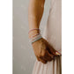 Close-up of a person's wrist wearing multiple pearl bracelets on a neutral background