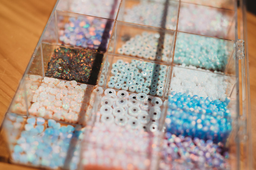 Assorted beads in a clear container on a wooden surface opal connectors 