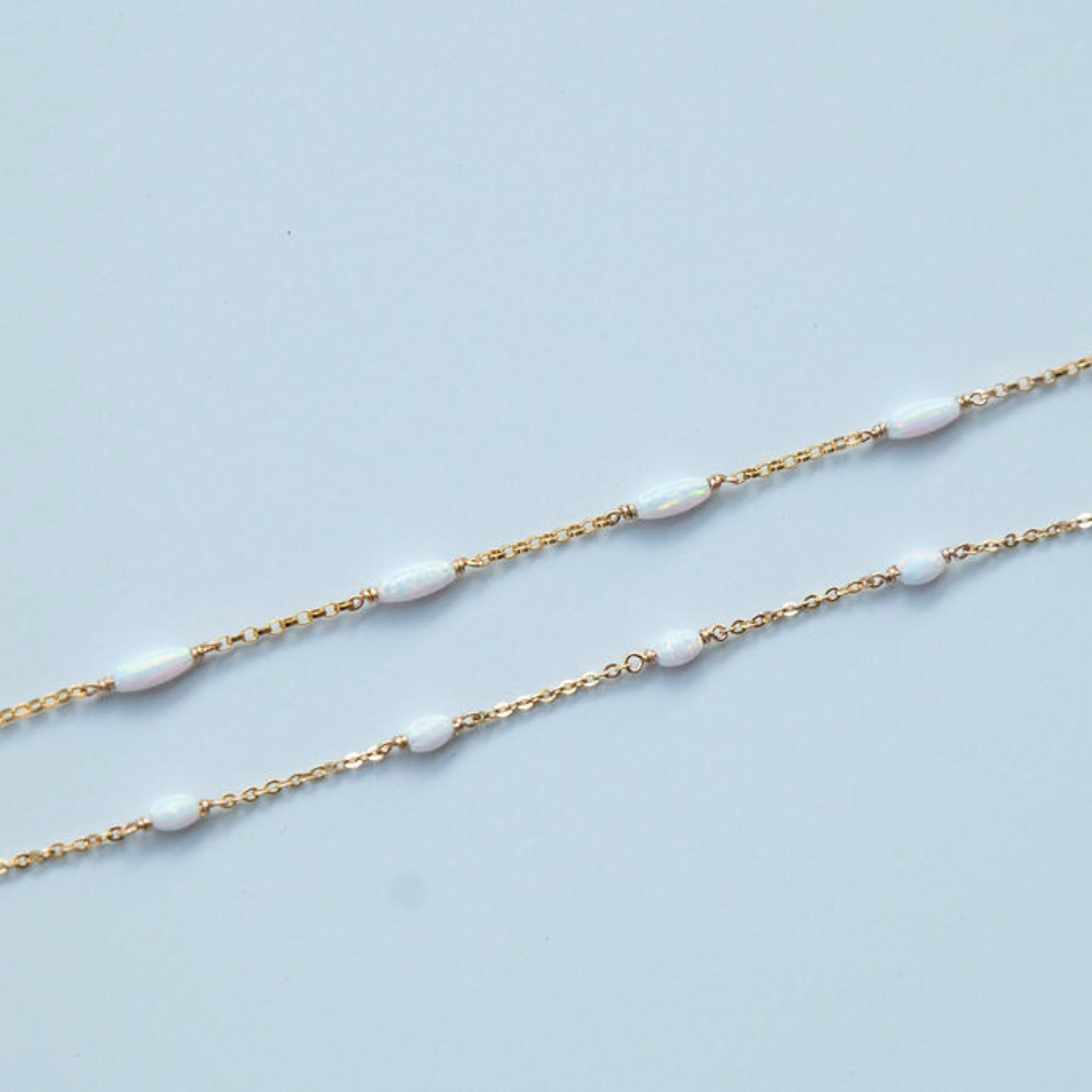 Gold chain with white beads on a light blue background