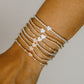 Close-up of a wrist wearing multiple beaded bracelets on a neutral background