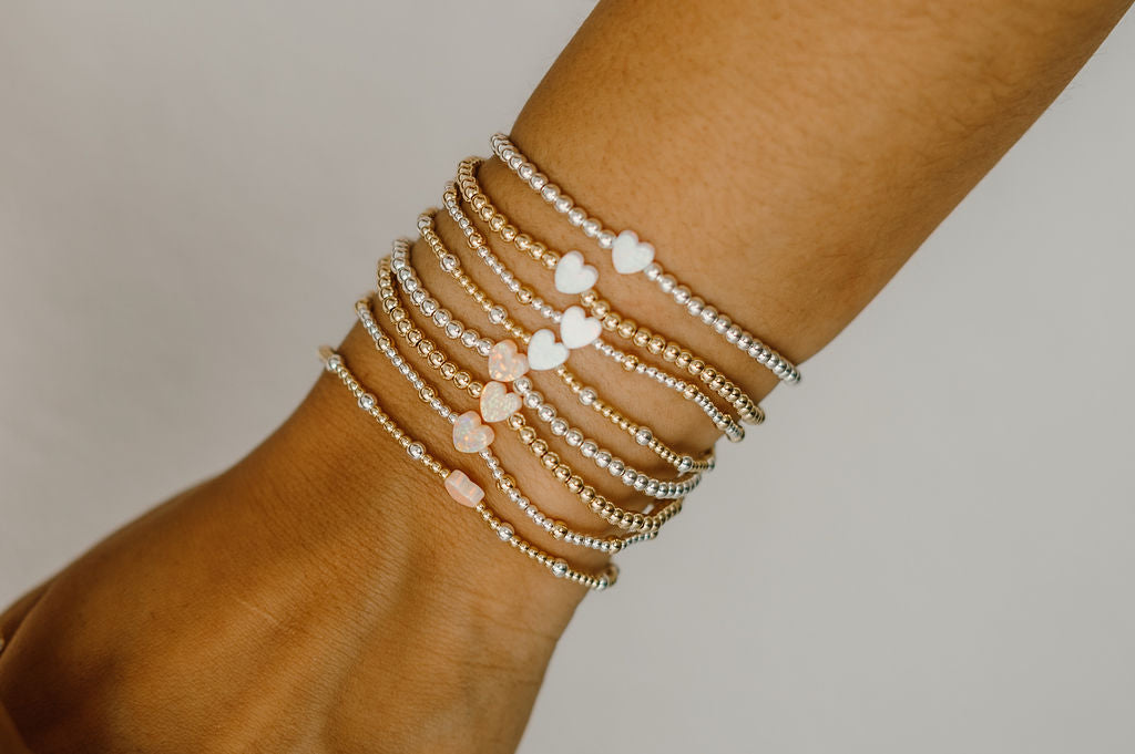 Close-up of a wrist wearing multiple beaded bracelets on a neutral background