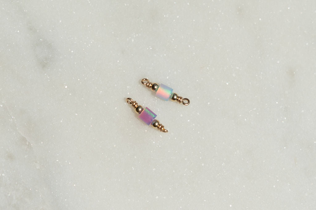 Two gold and pink beaded connectors on a light gray background