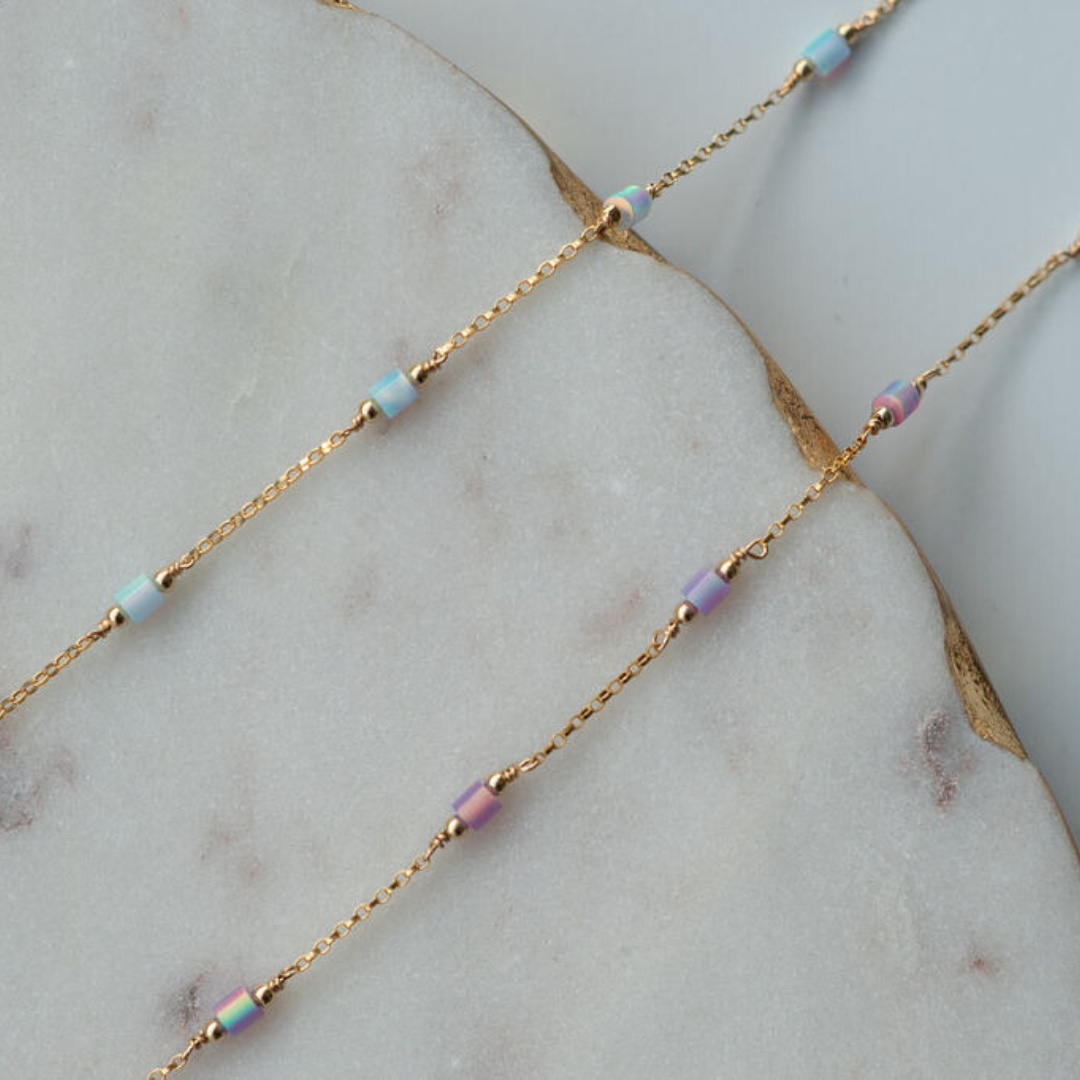 Gold chain necklace with small beads on a marble surface