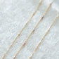 Gold chain necklace with small pearls on a white fabric background