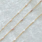 Two gold necklaces with pink pearls on a light gray background