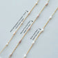 Three gold necklaces with pearl accents on a light gray background