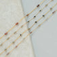Gold fill chain necklaces with small beads on a textured surface