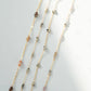 Layered necklace with beads on a light gray background