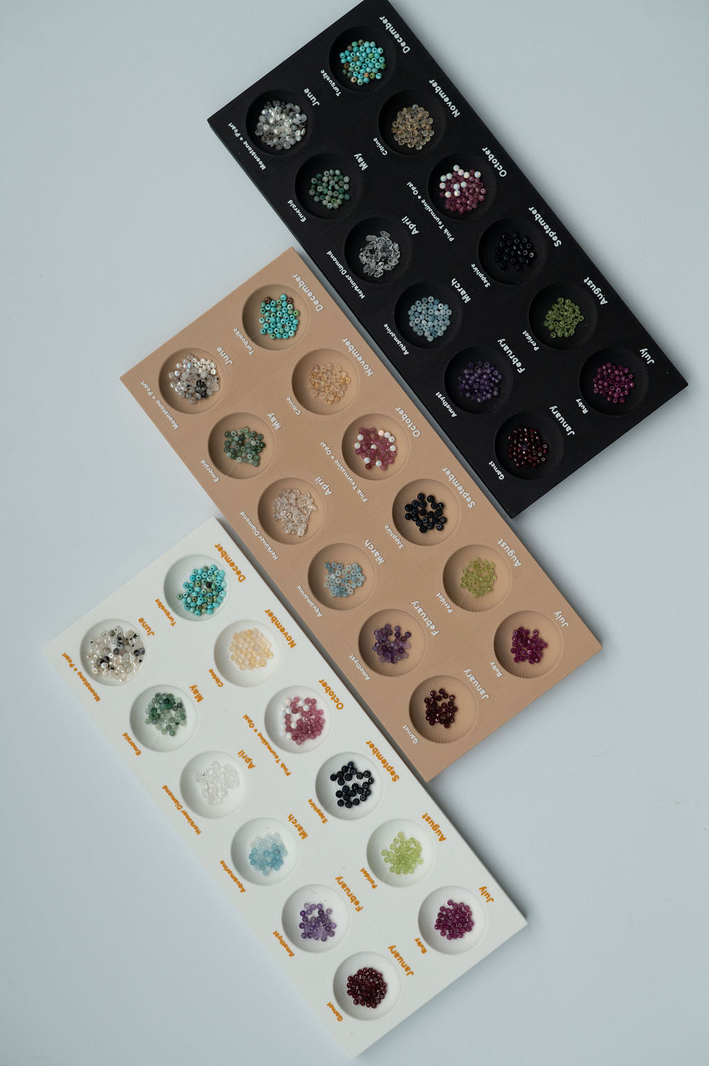 Three trays of gemstone samples on a light gray background