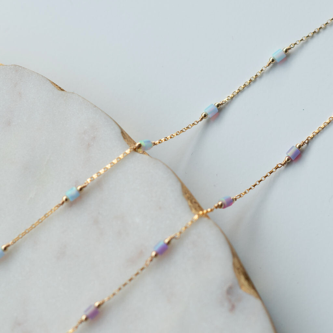 Gold chain necklace with small beads on a marble surface
