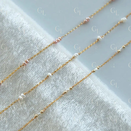 Gold chain necklaces with small pearls on a white towel