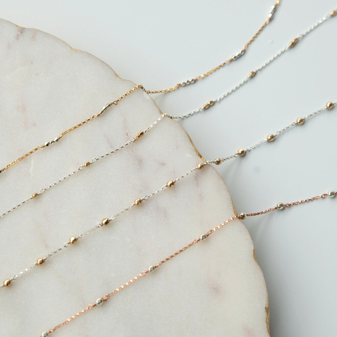 Three gold necklaces of different lengths on a marble surface