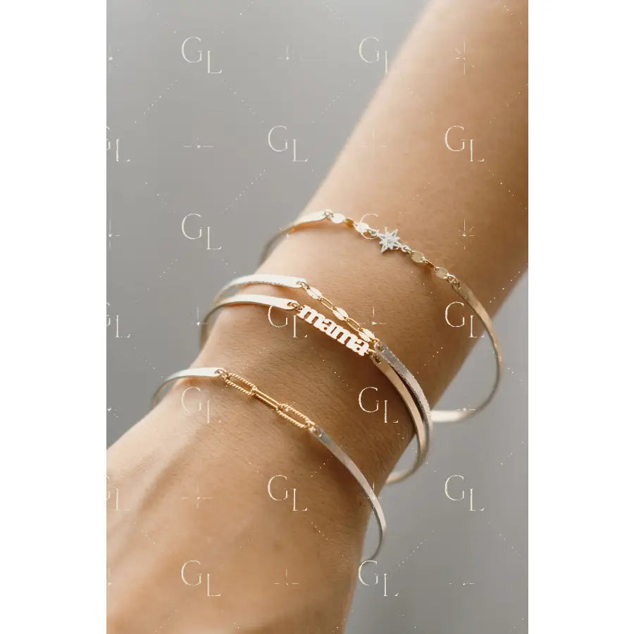 Close-up of a wrist wearing multiple gold and silver bracelets on a neutral background