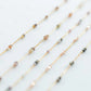 Set of thin gold necklaces with small beads on a light background