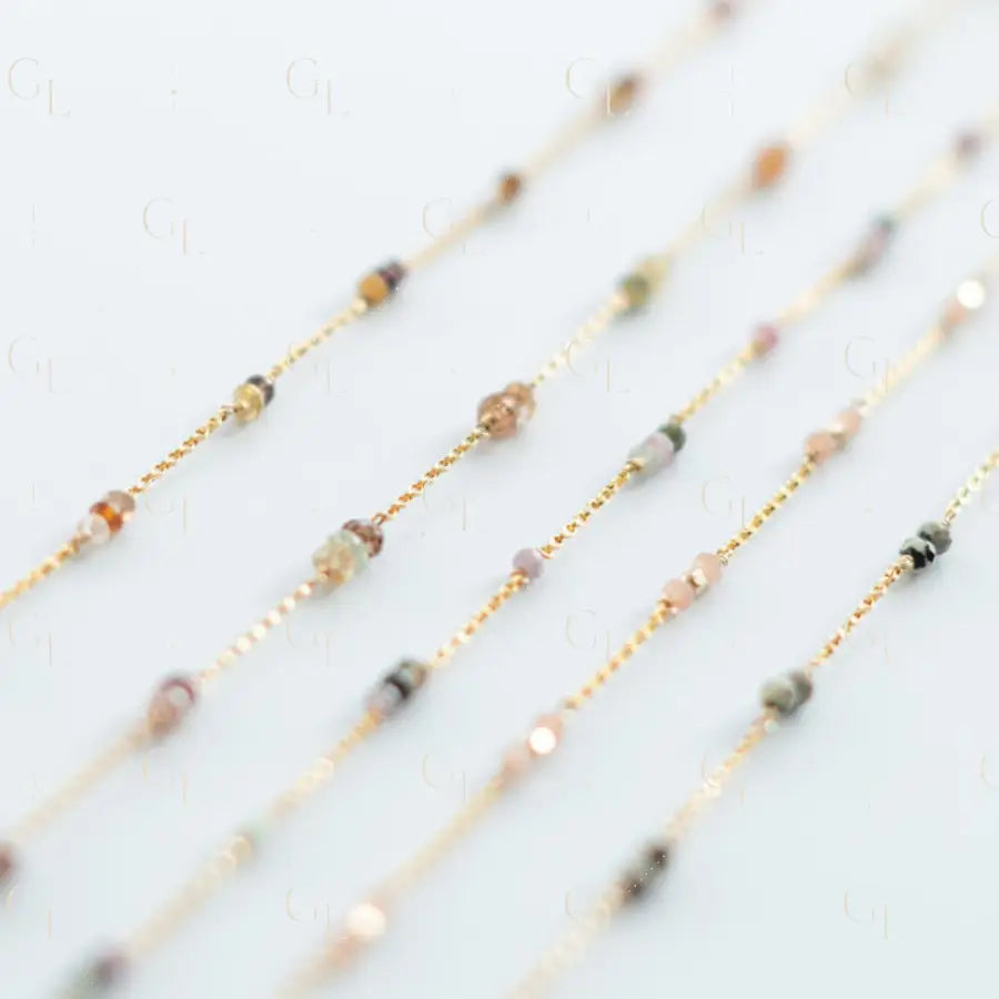 Set of thin gold necklaces with small beads on a light background