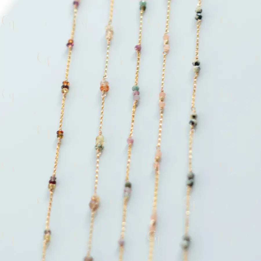 Three beaded necklaces with multicolored beads on a light gray background