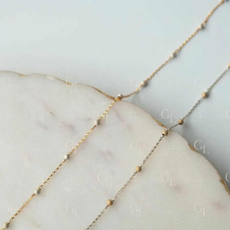 Delicate gold fill chain on a marble surface