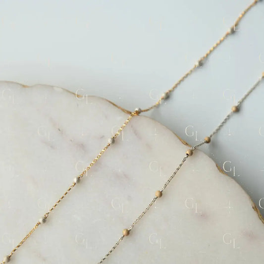 Delicate gold fill chain on a marble surface