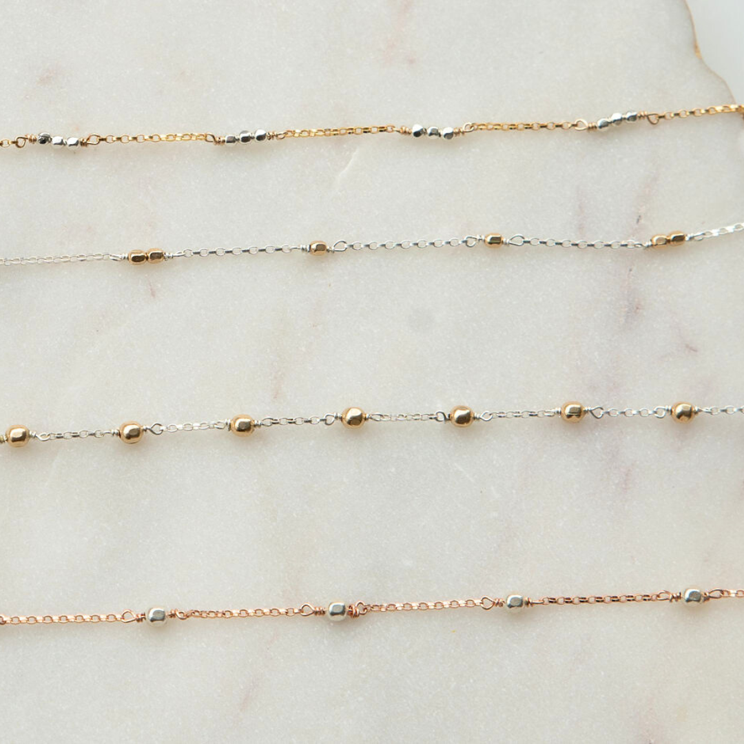 Three gold necklaces on a marble surface