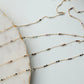 Gold chain necklace with small beads on a marble surface