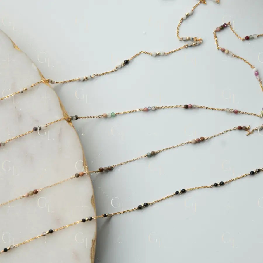 Gold chain necklace with small beads on a marble surface