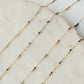Gold chain necklace with small beads on a marble surface