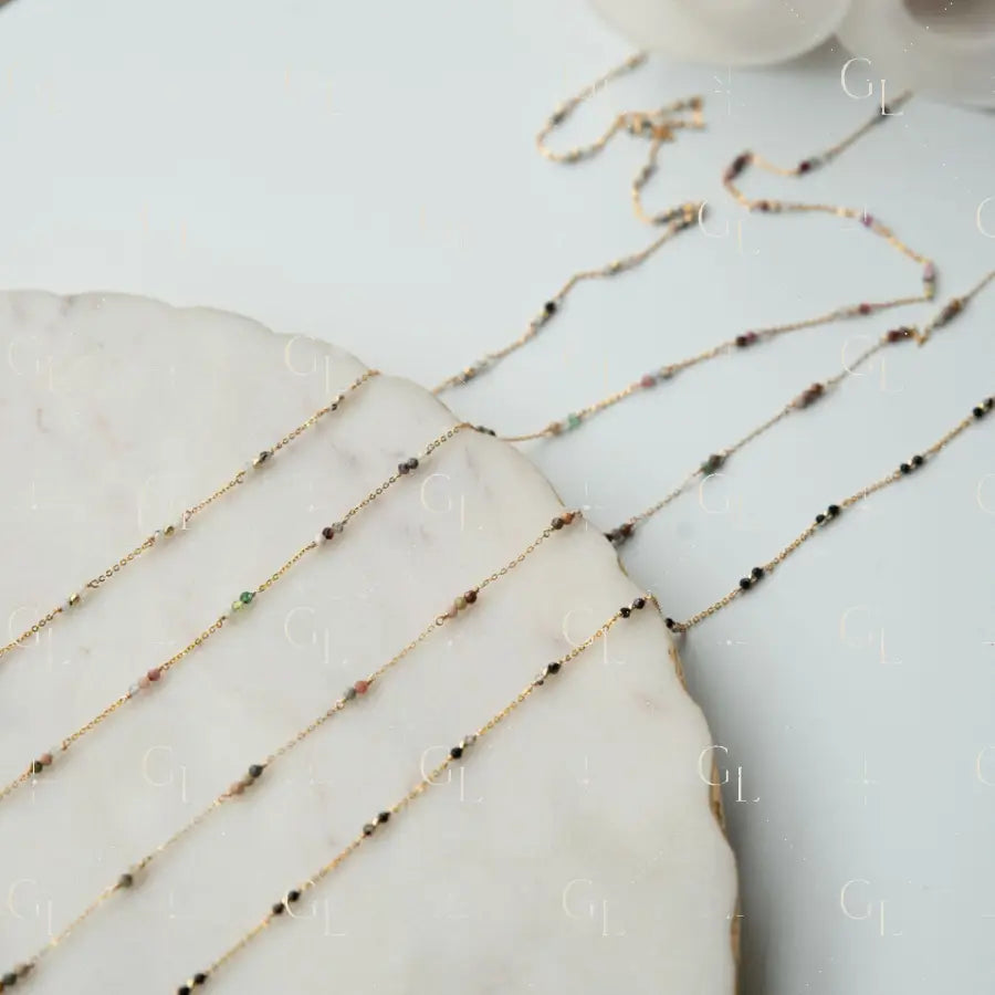 Gold chain necklace with small beads on a marble surface