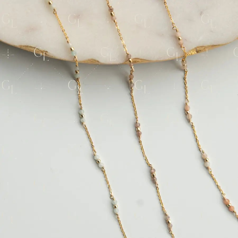 Gold chain necklace with small beads on a light gray surface