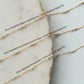 Three gold necklaces with gemstones on a marble surface