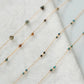 Delicate gold necklace with small beads on a white fabric background