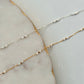 Two gold and silver beaded necklaces on a marble surface