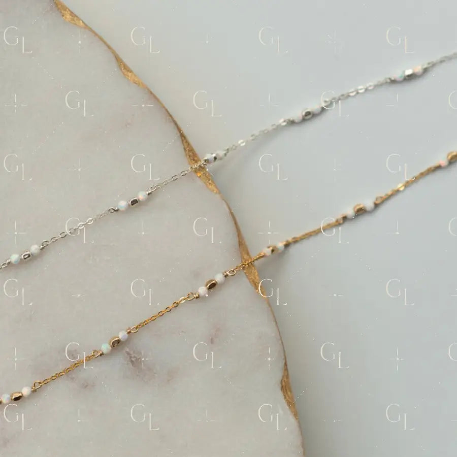 Two gold and silver beaded necklaces on a marble surface