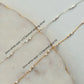 Two gold necklaces with white opal beads on a marble surface