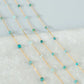 Gold chain with turquoise beads on a textured surface