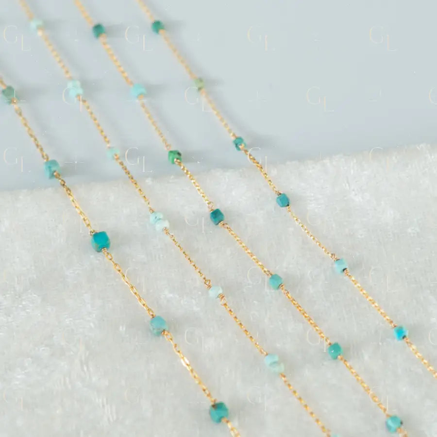 Gold chain with turquoise beads on a textured surface