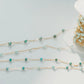 Gold chain with turquoise beads on a light gray background