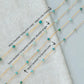 Turquoise beaded necklace with chain types labeled on a light gray background